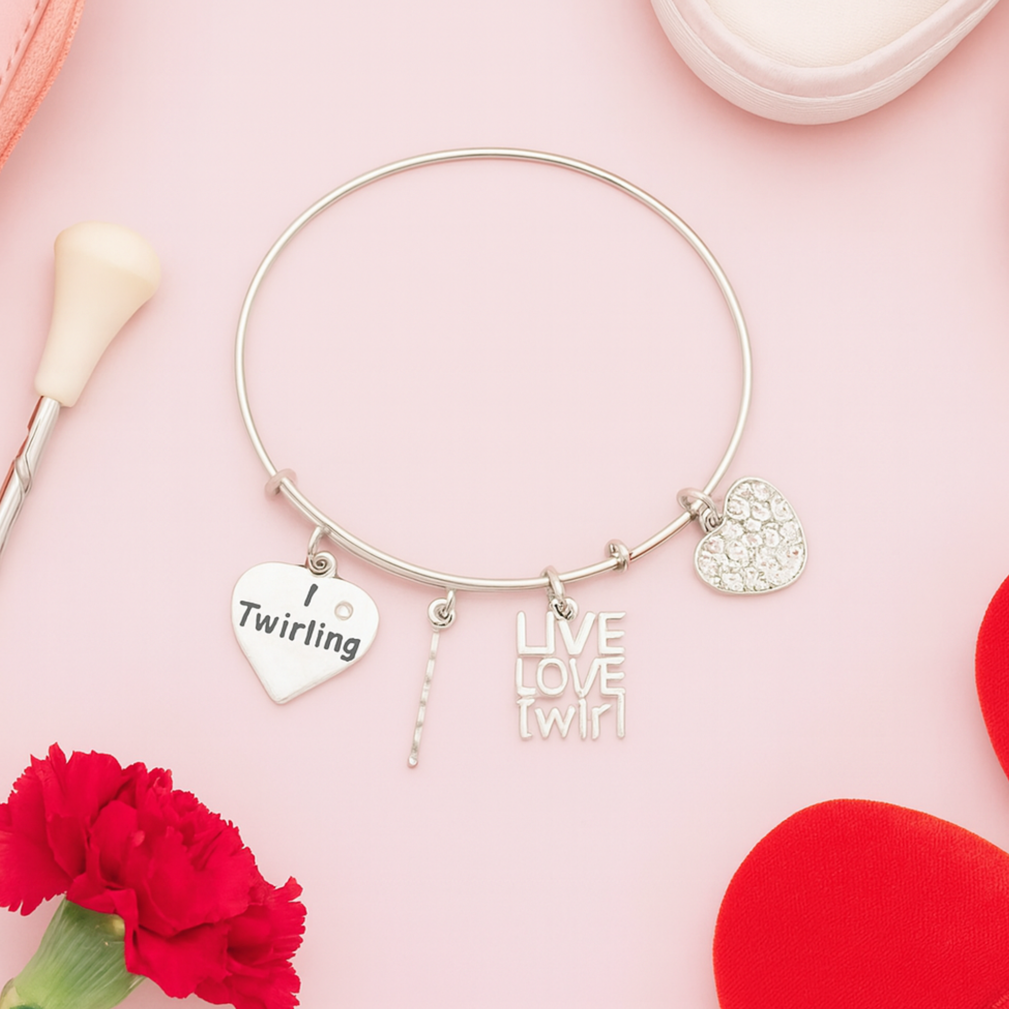 Twirling charm bracelet for baton twirlers displayed on pink background with decorative flowers