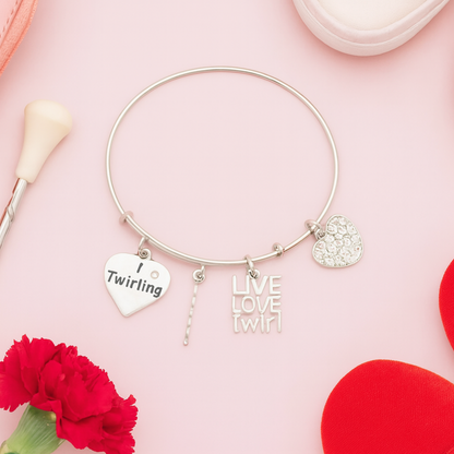 Twirling charm bracelet for baton twirlers displayed on pink background with decorative flowers