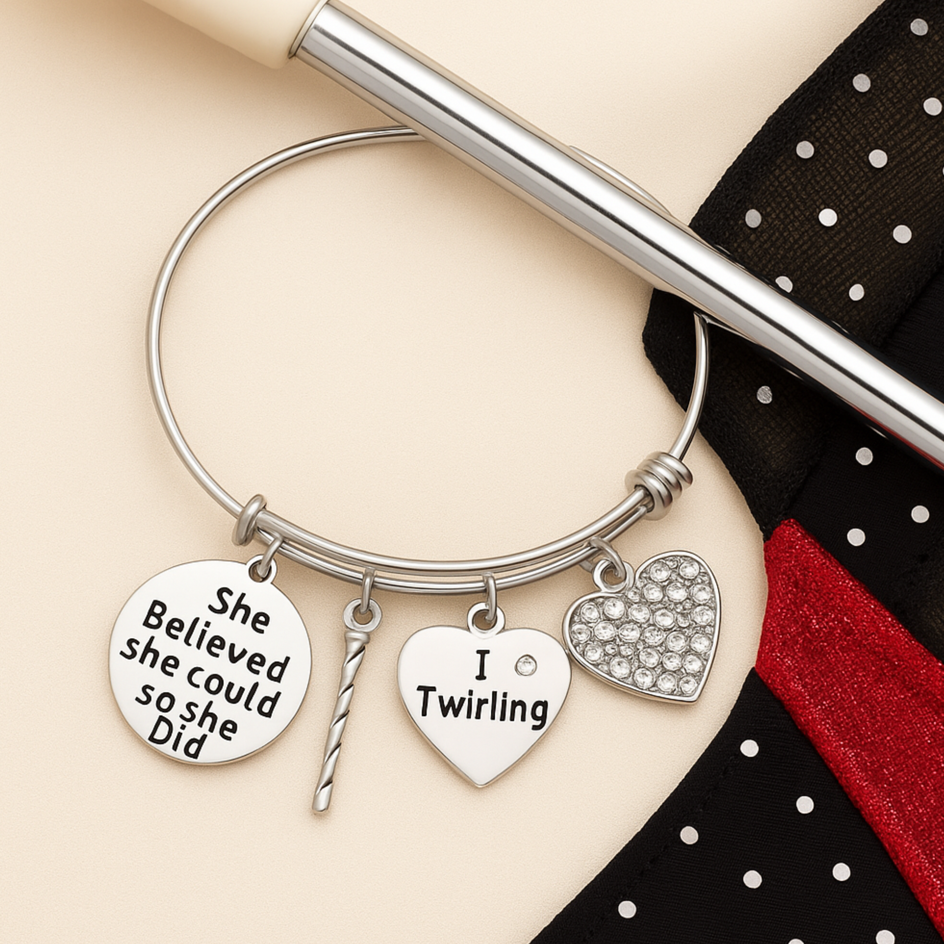 Close-up of silver plated twirling bracelet with engraved charms on a neutral background with pen for scale