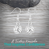 Silver volleyball drop earrings with french hook displayed on rustic wooden surface