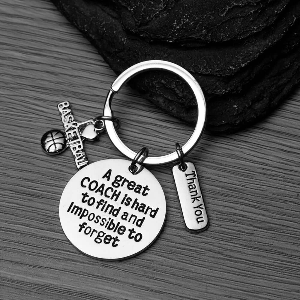 Engraved basketball coach keychain with charms displayed on basketball surface