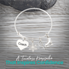 Figure skating bangle bracelet with coach heart charm displayed on rustic gray wooden surface