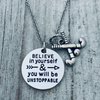 Silver motivational field hockey necklace displayed on textured gray background with disc and sticks