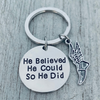 Detailed view of silver running shoe charm and 'He Believed He Could So He Did' disc on keyring