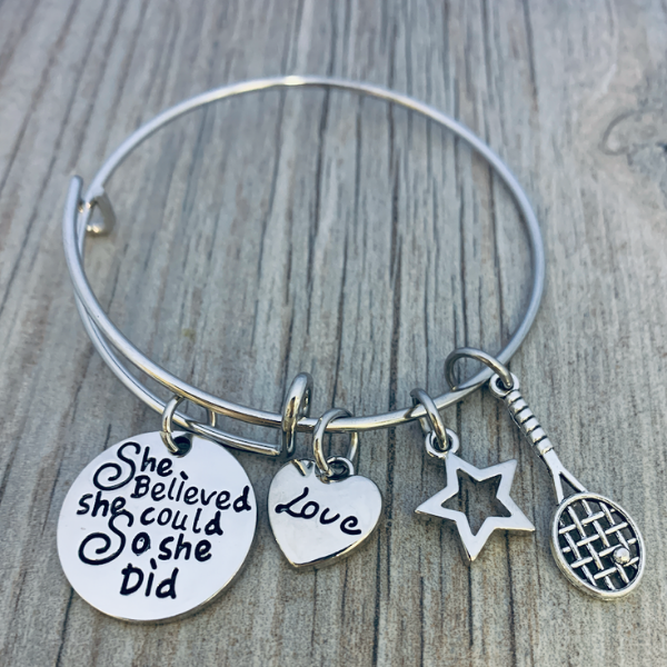 Silver tennis bracelet with engraved disc and sport charms on rustic wood, perfect gift for tennis players