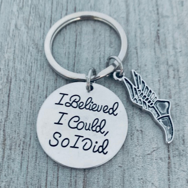 Detailed view of silver running shoe charm and 'I Believed I Could So I Did' motivational disc