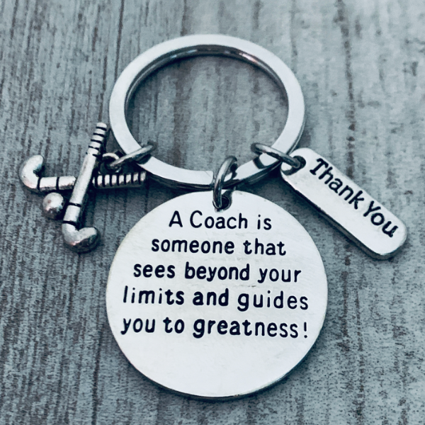 Round engraved charm reading A Coach Sees Beyond Your Limits on keychain with field hockey sticks charm