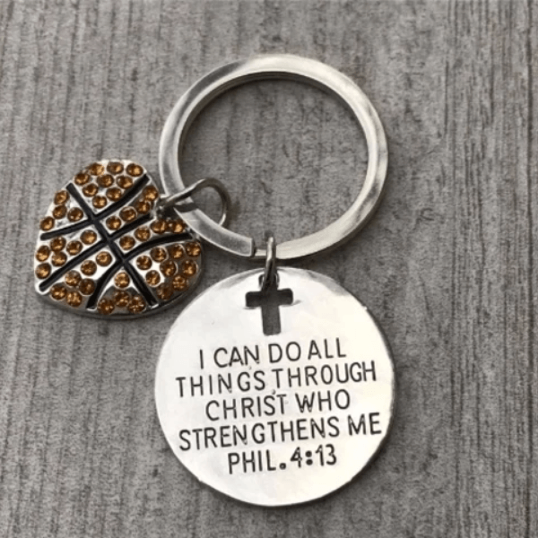 Motivational softball keychain with Bible verse and detailed stitching charm on gray wood textured background