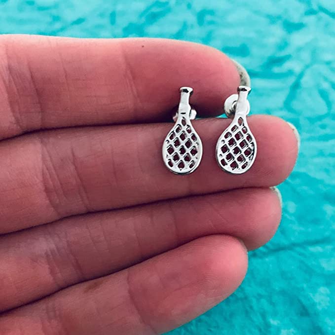 Close-up of tennis racket earrings on hand, showing scale and intricate details