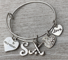 Personalized silver field hockey bangle bracelet with letter charm and heart charms on rustic wood surface