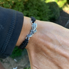 Lifestyle image: Track and Field bracelet worn on wrist outdoors, stacked with other bracelets