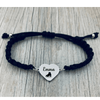 black bracelet with skate shoe engraved charm placed on wooden background