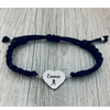 Lifestyle photo of navy rope bracelet with engraved running charm on wood surface