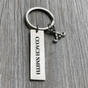 Close-up of engraved bar keychain with custom name on gray wood table