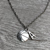 Close-up of necklace with basketball and “K” charm resting on wood background