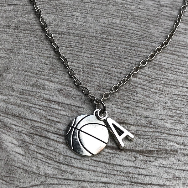 Close-up of necklace with basketball and “K” charm resting on wood background
