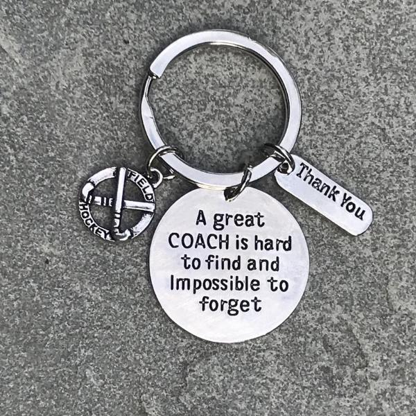 Silver coach appreciation keychain displayed on fabric with engraved quote and field hockey stick charm