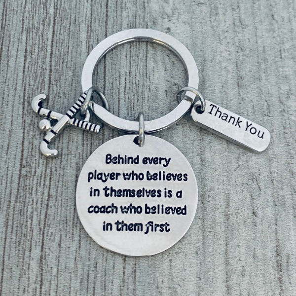 Round engraved charm reading Behind Every Player quote from field hockey coach keychain