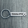 Engraved field hockey bar keychain with personalized name and number displayed on wooden background