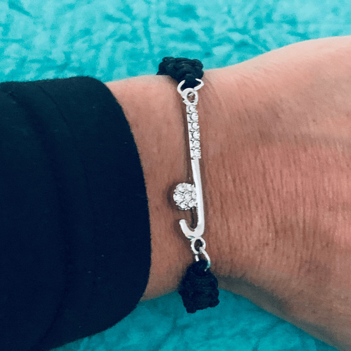 Side view of field hockey stick rope bracelet worn on wrist, showing the detailed silver charm
